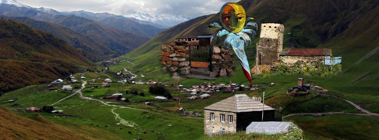 A photograph of the Ushguli valley with one of Fridon Nizharadze’s paintings set into the sky: a golden face inside a sun, with turquoise rays and red beneath it.